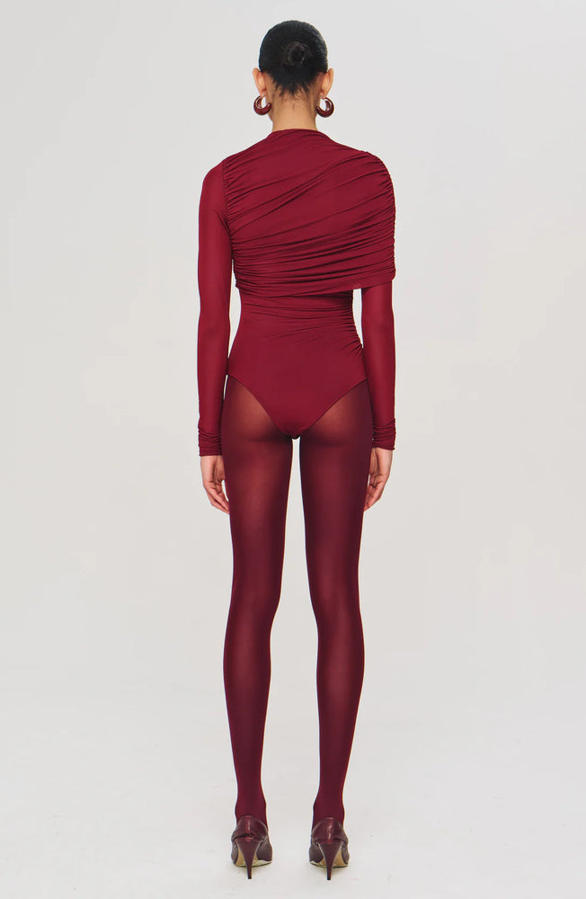 Designed to flatter from every angle, the Zarina Bodysuit is defined by sculptural ruching and a sleek, asymmetrical overlay. Crafted in ultra-soft jersey, it shapes the frame with subtle drama.